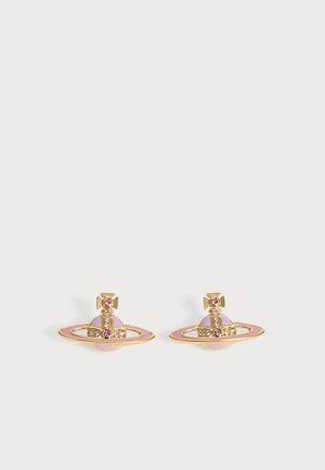 Paire de clous d’oreilles en forme de planète dorés et roses avec de petites pierres précieuses roses sur un fond clair uni.