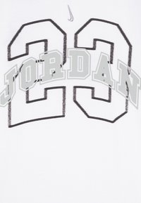 Bijela majica s velikim sivim tekstom "JORDAN" i brojem "23" u podebljanom, blokiranom fontu, s malim crnim Nike logom iznad.
