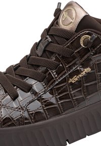 Baskets marron foncé avec texture crocodile, semelle épaisse texturée, lacets croisés, logo Tamaris doré et languette rembourrée avec emblème circulaire.