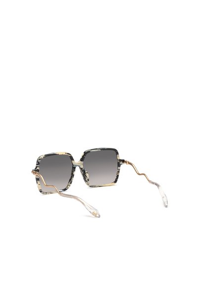 Lunettes de soleil carrées avec montures à motifs noirs et crème, verres foncés dégradés et branches dorées en forme de serpent avec extrémités courbées transparentes.