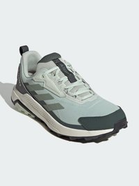 Baskets de sport vert clair avec une tige en mesh, accents vert foncé, semelle extérieure noire antidérapante, fermeture à lacets et une languette à l'arrière.