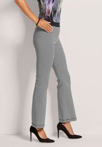 Zwart-witte chevron-patroon broek met een rechte pijpontwerp, gecombineerd met zwarte hoge hakken, voorzien van een aansluitende tailleband.