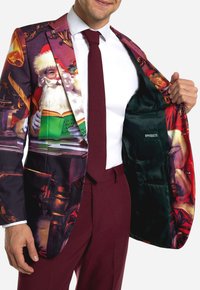 Barvit blazer z zimskim motivom, ki vključuje Božička, zlatimi detajli in bordo podlogo. Notranjost ima žepno oznako z napisom "OPPOSUITS."