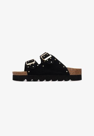 Sandalias de ante negro con dos hebillas ajustables, remaches dorados y una plantilla de corcho texturizada. Cuenta con una suela ondulada para mayor agarre.