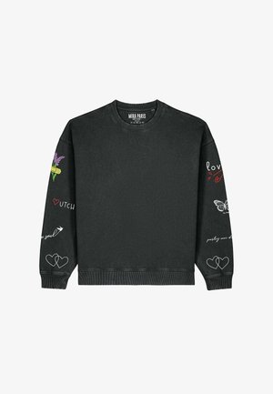 Fekete pulóver kerek nyakkivágással, hosszú ujjal és különféle színes hímzett díszítésekkel, köztük virágokkal, szívvel és felirattal.