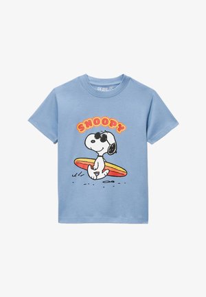 T-shirt bleu clair avec un graphisme de Snoopy portant des lunettes de soleil et tenant une planche de surf jaune et rouge, avec le texte "SNOOPY" au-dessus.