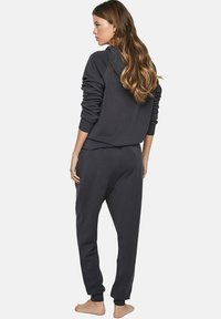 Donkergrijze sweatshirt en jogger set van zachte stof. De sweatshirt heeft raglanmouwen, terwijl de joggers elastische manchetten en een elastische tailleband hebben.
