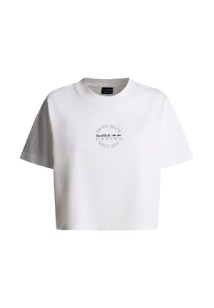 Baltu, īslaicīgi nogrieztu T-kreklu ar apaļu kakla izgriezumu, uz kuras priekšpuses centrā atrodas Red Bull Racing logotips un uzraksts "On the Track Since 2004".