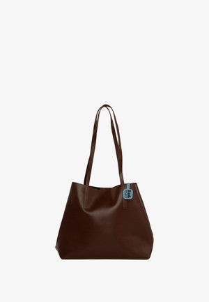 Hnedá kožená taška s dvoma dlhými rúčkami, hladkým povrchom a malou modrou visačkou pripevnenou na jednej rúčke. Jednoduchý, jednoduchý dizajn.