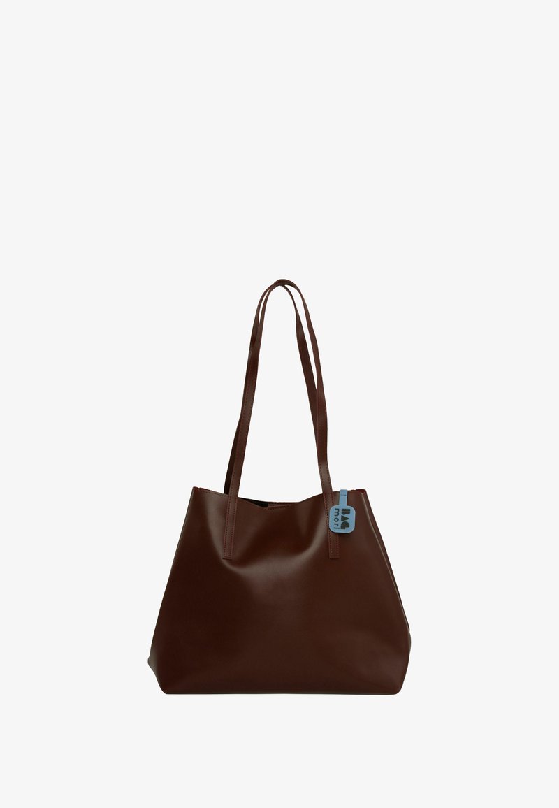 Rjava usnjena torba z dvema dolgima ročajema, gladko teksturo in majhno modro oznako, pritrjeno na en ročaj. Preprost, neokrašen dizajn.