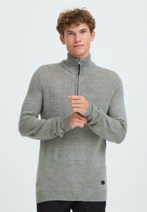 Graue Zip-Kragen-Strickjacke aus einem strukturierten Strickstoff, mit hohem Kragen und gerippten Bündchen. Dezentes Markenlabel an der untere Seite.