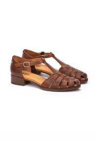 Sandalias de piel marrón con diseño de tira en T y puntera abierta. Presentan un tacón cuadrado bajo y detalles frontales trenzados. Hebilla ajustable en el tobillo.