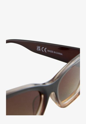 Sončna očala v rjavo obarvanem tonu s prozornim svetlo rjavim okvirjem, temno rjavimi ročaji in vtisnjenimi podrobnostmi, ki vključujejo "CE" in "MADE IN CHINA."