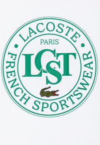 Hvit t-skjorte med en grønn rund logo med teksten "LACOSTE PARIS" og "FRENCH SPORTSWEAR", samt et brodert krokodille-design.