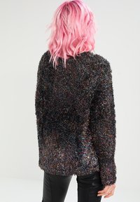 Suéter de manga larga negro y multicolor de textura suave. Textura blanda, corte holgado, con un escote redondo y puños acanalados.
