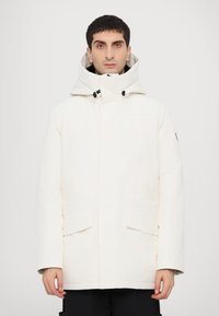 Veste à capuche blanche avec fermeture éclair sur le devant, grandes poches à rabat et coupe décontractée. Le matériau semble texturé avec une finition mate.