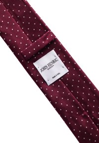 Vinröd slips av texturerad tyg med vita prickar, med en etikett som har "JOHN HENRIC SWEDEN" och "Tillverkad i Italien"-detaljer.