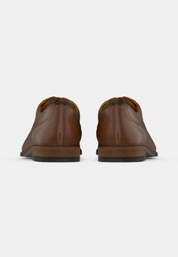 Chaussures en cuir marron avec une finition lisse, bouts ronds et un petit talon en bois. L'arrière présente des détails de couture discrets.