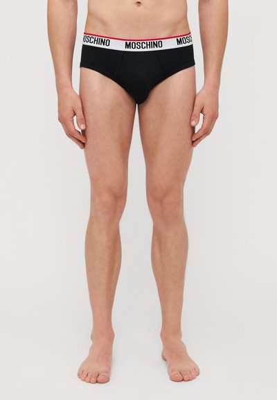Caleçons pour hommes noirs en coton doux. Dotés d'une ceinture blanche avec le logo rouge "MOSCHINO". Forme classique de slip et design minimaliste.