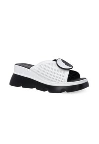 Bílé perforované slip-on boty s černým akcentem a chunky černou podrážkou. Obsahují kruhový dekorativní prvek na svršku. Texturovaný povrch.