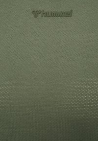 Groen gestructureerde stof met gegraveerd Hummel-logo en bijensymbool nabij het bovenste midden.