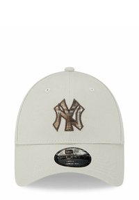 Gorra de béisbol beige con un logotipo en relieve "NY" en marrón. Presenta un visera curvada y seis agujeros de ventilación en la parte superior. Estilo 9FORTY.