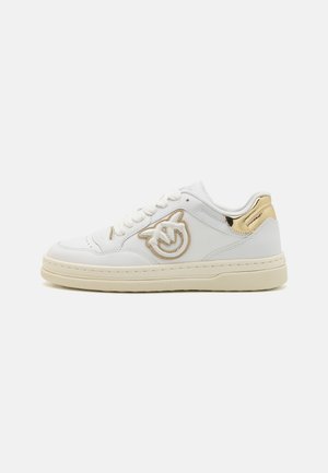 Sneakers bianchi in pelle con suola crema, accenti dorati sul tallone e logo ricamato dorato sul lato. Presentano un design con lacci.