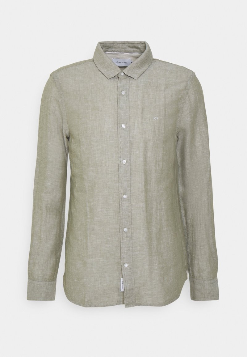 Chemise en lin vert clair à manches longues, devant boutonné et col. Présente un logo discret sur la poitrine et des poignets classiques à boutons.