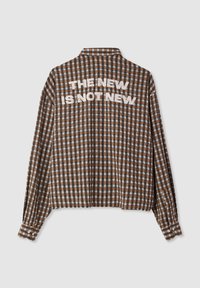 Camicia a quadri marrone e crema con maniche lunghe, presenta la scritta "IL NUOVO NON È NUOVO" in bianco sulla schiena. Tessuto morbido, polsini con bottoni.