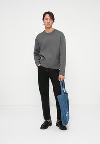 Grå genser med rund hals, svarte jeans, svarte sko og en blå totebag. Teksturen på genseren ser glatt ut; vesken har et denimutseende.