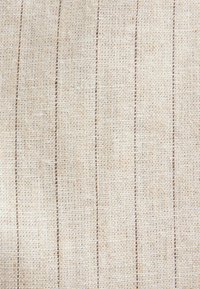 Tissu tissé beige avec des rayures verticales brunes régulièrement espacées et une texture grossière visible en gros plan.