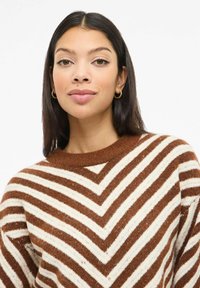 Hnědý a krémový pruhovaný pletený svetr se vzorem ve tvaru rybí kosti, s kulatým výstřihem a texturovanou látkou.