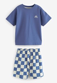 T-shirt en coton bleu avec un petit logo représentant un soleil et l'océan, associé à un short à carreaux bleus et crème avec une taille élastique.