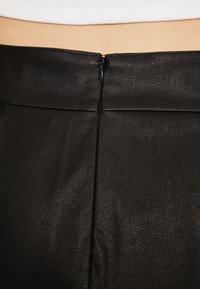 Zwarte leren rok met een gladde textuur, een ritssluiting aan de achterkant en een op maat gemaakte uitstraling met subtiele stiksel details.