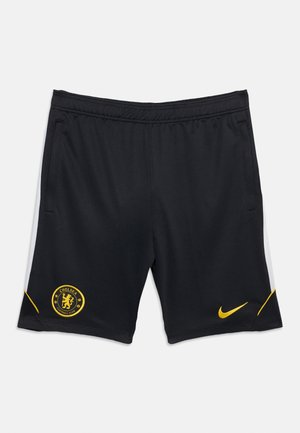 Čierne športové šortky so žltým logom Chelsea Football Club na ľavej nohe a žltým znakom Nike na pravej nohe.