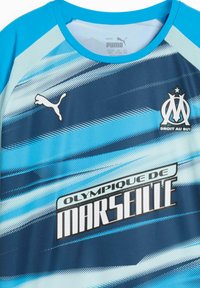 Sportovní dres Puma v modrém gradientu s diagonálními pruhy. Na přední straně je logo Olympique de Marseille a text "Droit au But".