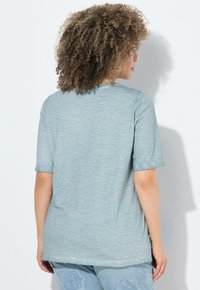 Camiseta de manga corta azul claro, con una tela suave y texturizada, cuello redondo y un corte relajado. Presenta aberturas laterales en el dobladillo.