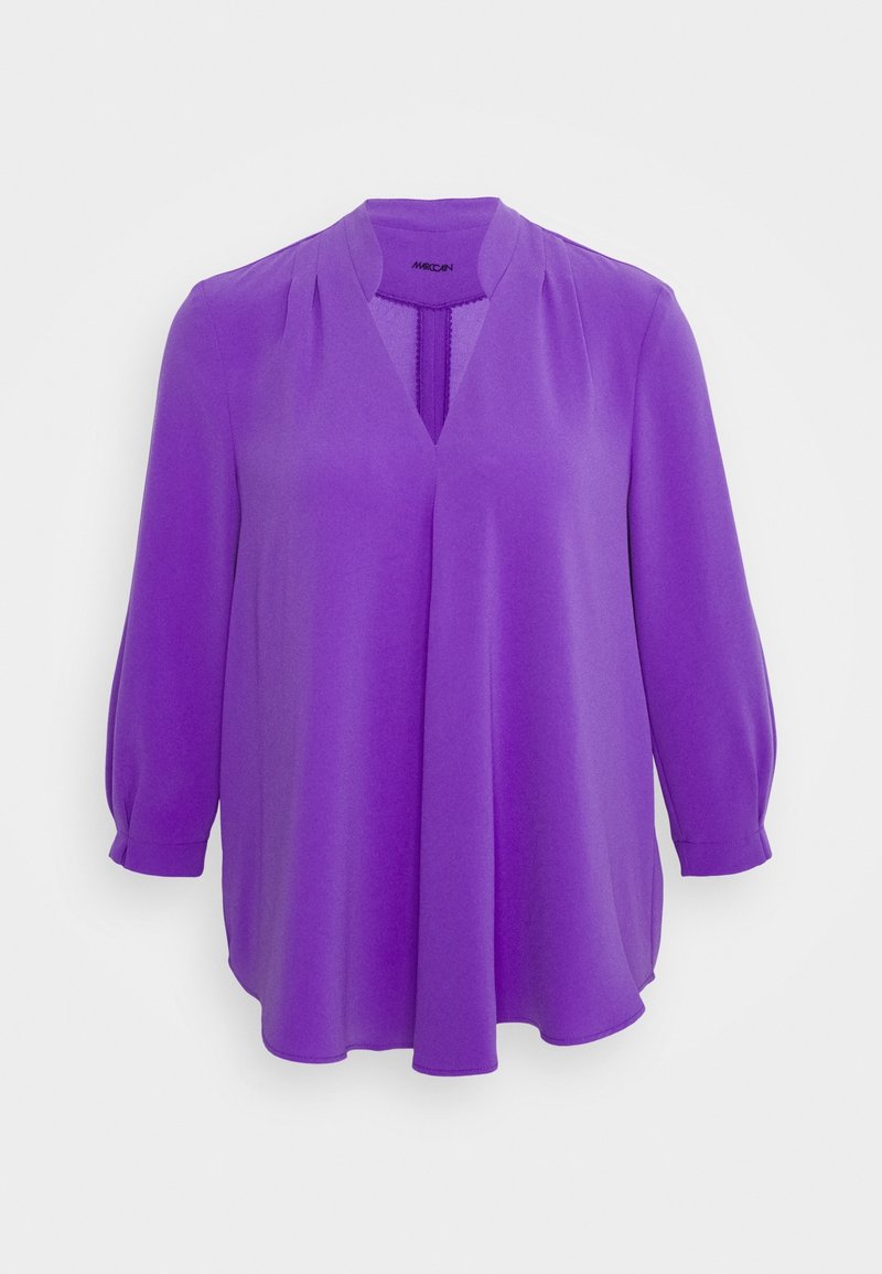 Blouse mauve à manches longues avec décolleté en V, détail plissé sur le devant et poignets légèrement froncés sur un fond blanc uni.