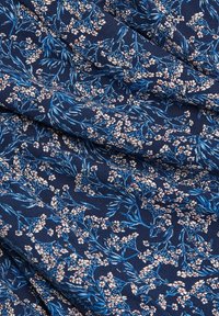 Tissu bleu marine avec un motif floral comprenant des fleurs roses et bleues sur des branches entrelacées. La texture semble lisse et légère.
