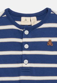 Μπλε και λευκό ριγέ παιδικό φορμάκι με τρία λευκά κουμπιά στο μπροστινό μέρος και ένα μικρό κεντ ητό καφέ αρκουδάκι στο στήθος.