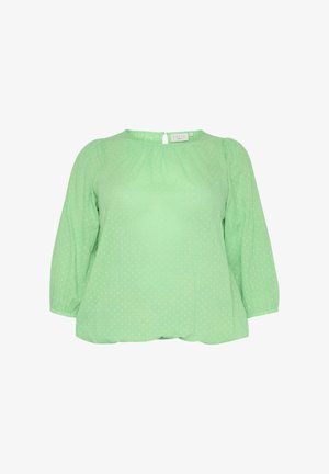 Blouse verte à pois avec un col rond, des manches bouffantes mi-longues, des détails froncés et une fermeture par un clé. Tissu léger.