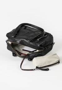 Borsa a mano in pelle nera con due manici, scomparto principale con zip che rivela una fodera a righe, include una piccola pochette beige con zip.
