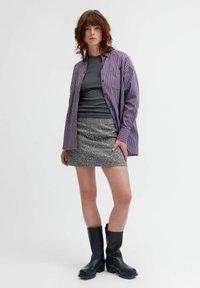 Dryžuota marškinėlių camisa raudona ir mėlyna, pilkas prigludęs topas, sidabrinės tekstūros mini sijonas, juodi kelių ilgio batai. Paprastas, šiuolaikiškas stilius.