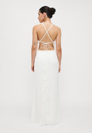 Robe en satin blanc au dos nu, avec des bretelles entrecroisées et un détail de taille nouée. Texture lisse, silhouette longue jusqu'au sol.