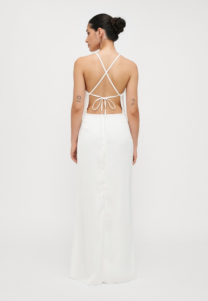 White satin dress with a backless design, featuring crisscross straps and a tied waist detail. Sleek texture, floor-length silhouette.
