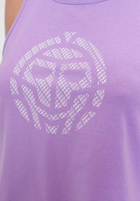 Lila Trägershirt mit einem weißen Grafikdesign, bei dem wiederholte Texte ein kreisförmiges Muster bilden, aus einem glatten, leichten Stoff gefertigt.