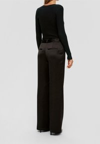Top negro de manga larga con textura acanalada, combinado con pantalones de talle alto, de corte recto y amplia, en una textura suave, con bolsillos traseros y un cinturón.