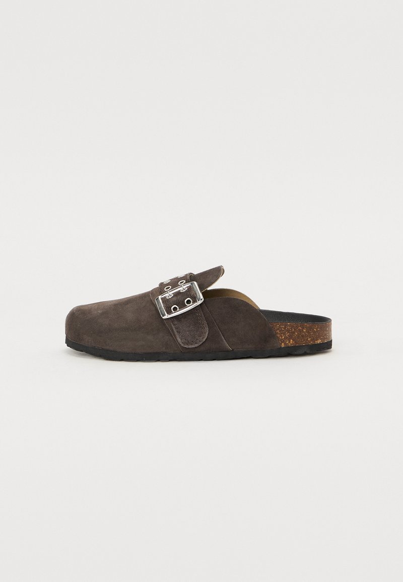 Donkergrijze suede instapper met een ronde neus, zilveren gesp detail, kurken voetbed en zwarte rubberen loopzool.