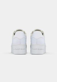 Białe skórzane sneakersy o gładkim wykończeniu, z grubą, białą podeszwą i subtelnym detalem logo z tyłu. Okrągły kształt pięty.