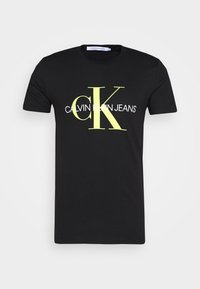 Czarny t-shirt z krótkim rękawem z dużym żółtym logo "cK" i białym napisem "Calvin Klein Jeans" na klatce piersiowej, w stylu z okrągłym dekoltem.